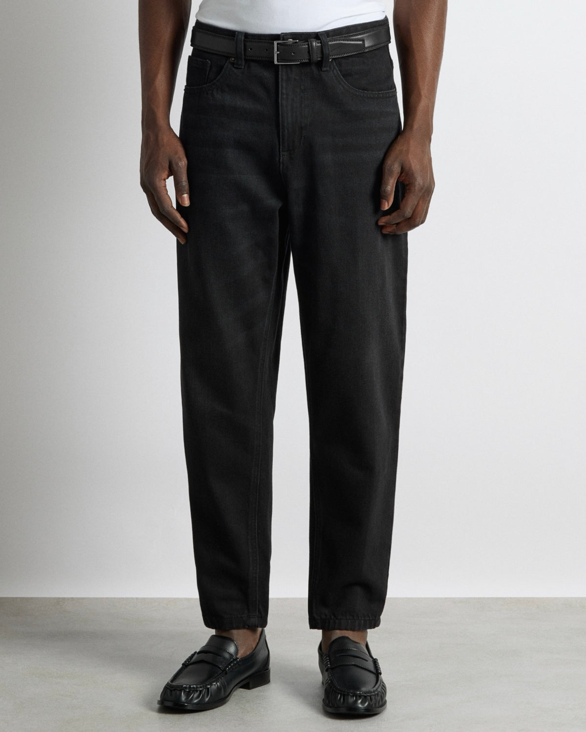Dettaglio jeans carrot fit nero con slavatura sulle cosce